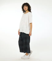 model in a wide leg deep grey pant, white pullover top with a large rounded neckline and an elbow length raglan sleeve. Top and pant both have a large checkered print woven into the fabric