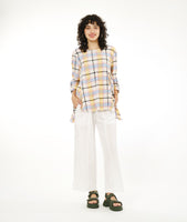 model in a wide leg white pant with a multicolor plaid top with a dipped hem on either hip and rolled sleeves