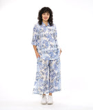 model in a wide leg pant with a split on either leg, with a matching button down blouse with rolled sleeves in a matching blue and black leaf print on a white background