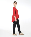 model in a slim black pant with a red pull over top with 3/4 sleeves, a round neckline, and a rounded high low hem with a full flowy body in the back