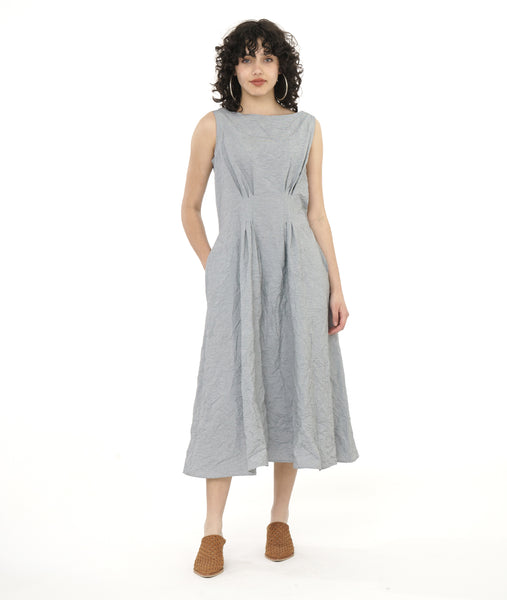 model in a white and grey pinstripe sleeveless dress with a crush texture. dress has a round, wide neck, tucks at the front and back waist and pockets