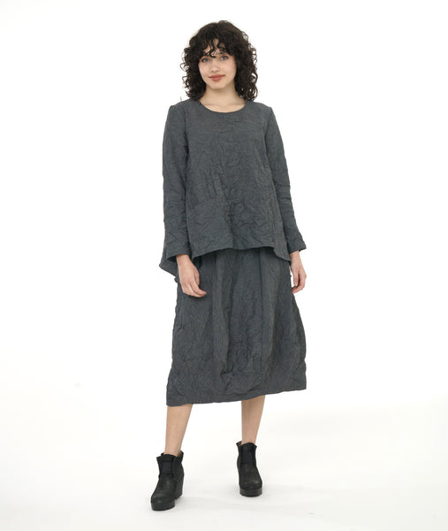 model in a grey and black pinstriped top with a crush texture to it. top has a boxy body with a draped hem on either side. worn with a matching skirt