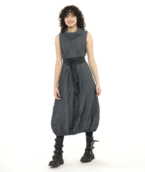 model in a black and grey pinstripe sleeveless dress with a crush texture. dress has an oversized cowl neck, tucks at the front and back waist, and an elastic gathering at the bottom hem creating a tulip shaped skirt