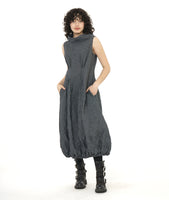 model in a black and grey pinstripe sleeveless dress with a crush texture. dress has an oversized cowl neck, tucks at the front and back waist, and an elastic gathering at the bottom hem creating a tulip shaped skirt