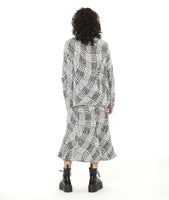 model in a black and white print skirt with a mermaid silhouette, worn with a matching boxy top with a small standing collar, long dolman sleeves, and a boxy fit