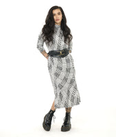 model in a black and white print shift dress with a small standing collar and long sleeves. dress is  midi length and has slits at the sides