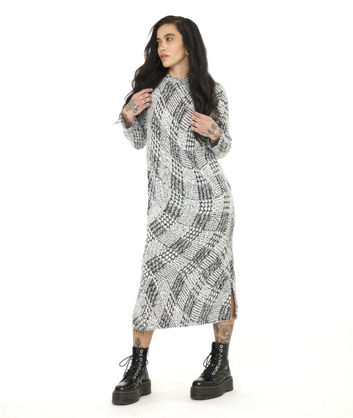 model in a black and white print shift dress with a small standing collar and long sleeves. dress is  midi length and has slits at the sides