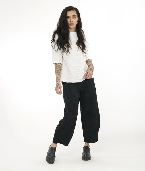model in a wide leg black textured pant, worn with a textured white pullover top with a short standing collar and 3/4 length raglan sleeves