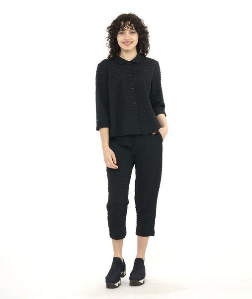 model in a black textured boxy button down blouse with a matching crop pant. blouse has a twin button detail and 3/4 sleeves with a split cuff
