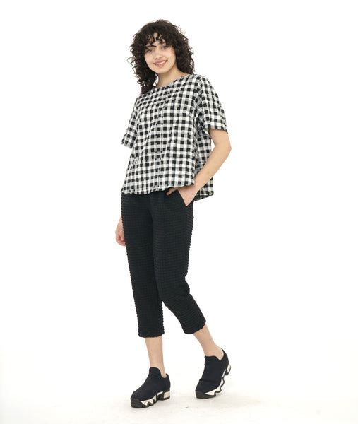 model in a short boxy plaid top with a textured black crop pant