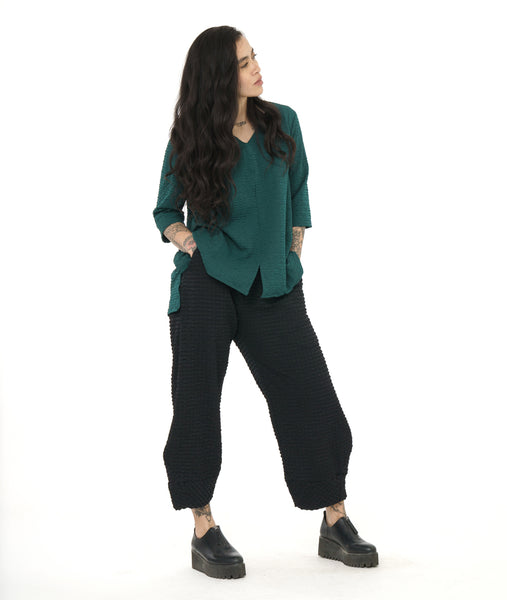 model in a textured black wide leg pant with a emerald green pullover top with the same texture. top has a split at the center front seam, v-neck, 3/4 sleeves and a low back hem