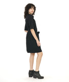 model in a textured black shift dress with a matching tie belt, deep exterior pockets, and elbow length raglan sleeves