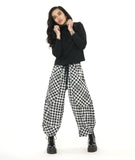 model in a black mock turtleneck top, worn with a textured black and white plaid print wide leg pant with a tapered ankle, oversized exterior pockets, and a black tie belt over the elastic waistband
