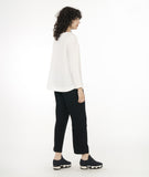 model in a slim black pant worn with a white pullover top with long sleeves, a round hem and round neckline with a triangle placket and button detail