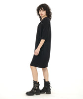 model in a black knee length shift dress with 3/4 sleeves, a squared neckline and pockets set in to the side seams