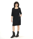 model in a black knee length shift dress with 3/4 sleeves, a squared neckline and pockets set in to the side seams