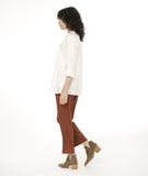 model in a slim rust color pant with a white long button down blouse with 3/4 sleeves, with a twin button detail on the placket and sleeve cuffs