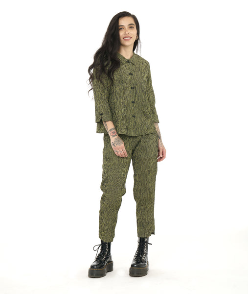 model in a slim green and black striped pant with a contrasting tuxedo stripe on the side and a stair step hem. worn with a matching boxy button down blouse with 3/4 sleeves with a split cuff and button detail