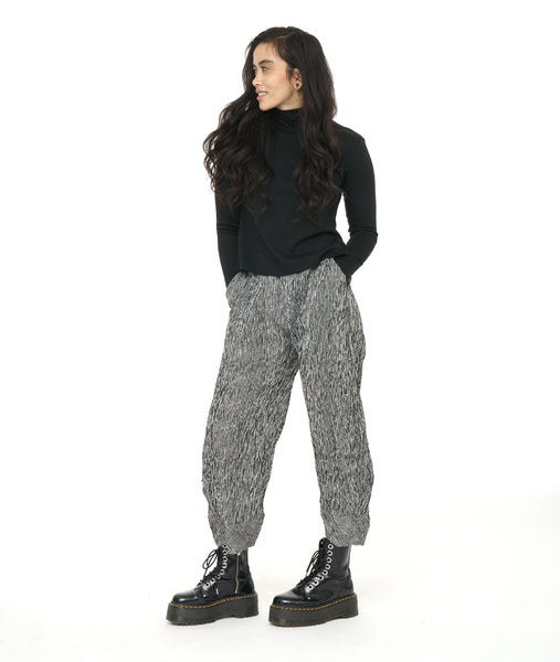 model in a black mock turtle neck top with a black and white striped pant with a wide leg and a tulip shaped tapering at the ankle