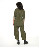 model in a wide leg green and black striped pant with a tulip shape at the ankle, created with tucks. worn with a matching button down blouse with a long rounded hem and rolled and buttoned sleeves