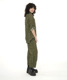 model in a wide leg green and black striped pant with a tulip shape at the ankle, created with tucks. worn with a matching button down blouse with a long rounded hem and rolled and buttoned sleeves