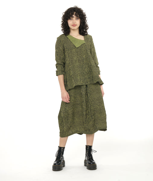 model in a tulip shaped black and green striped skirt worn with a swingy pullover blouse with an asymmetrical neckline and a contrasting half collar.