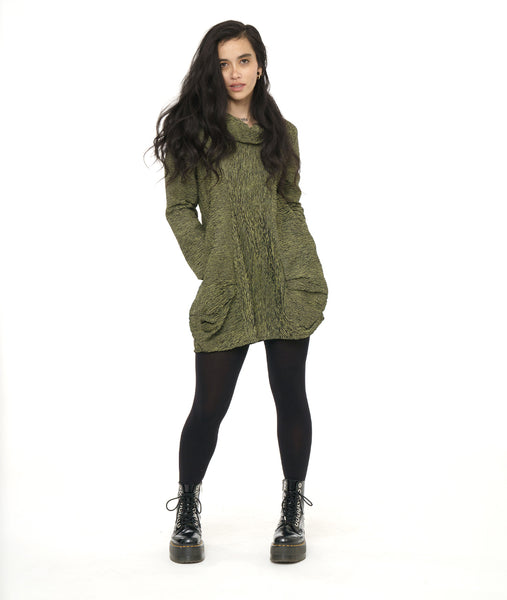 model in a black legging and boot, with a black and green striped tunic with a exaggerated cowl neck, long sleeves and pleating along the hips giving a full body