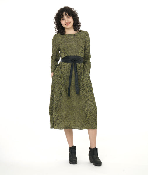 model in a black and green striped long sleeve tea length dress with angled seams on the skirt and bodice, meeting at the front and back center, worn with a black belt
