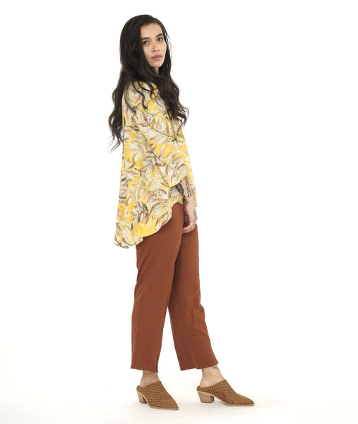 model in a yellow floral print blouse with a high-low hem, worn with a rust color slim leg pant
