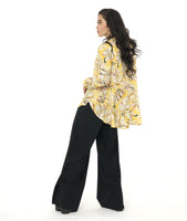 model in a yellow floral print blouse with a high-low hem, worn with a black wide leg pant