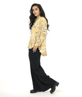 model in a yellow floral print blouse with a high-low hem, worn with a black wide leg pant