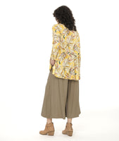 model in a yellow floral print blouse with a high-low hem, worn with a taupe color wide leg pant