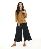 model in a wide leg black pant with an apron style panel overlay, worn with a yellow button down blouse with a twin button detail