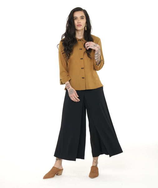 model in a black wide leg pant with a cross over apron panel in the front, worn with a yellow button down blouse