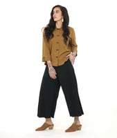 model in a black wide leg pant with a cross over apron panel in the front, worn with a yellow button down blouse