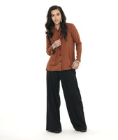 model in a wide leg black palazzo pant, worn with a rust color button down blouse with a round, standing collar and long sleeves