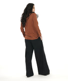 model in a wide leg black palazzo pant, worn with a rust color button down blouse with a round, standing collar and long sleeves