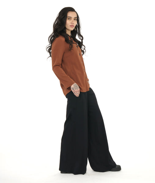 model in a wide leg black palazzo pant, worn with a rust color button down blouse with a round, standing collar and long sleeves