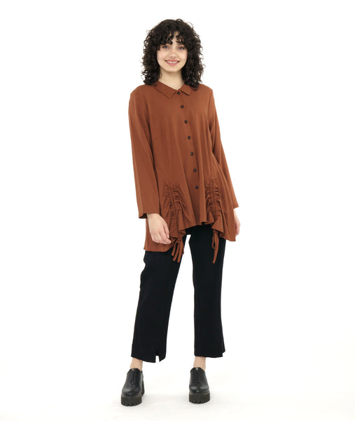 model in a slim black pant with a rust color button down blouse with an adjustable gather detail at each hip