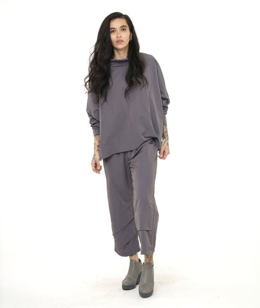 model in a slim grey pant with asymmertical seams along the leg, worn with a boxy pull over top in a matching fabric, with dolman sleeves, princess seams, and a rounded cowl neckline