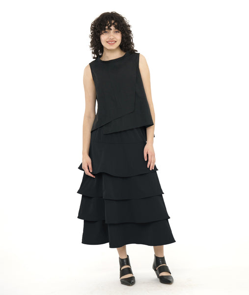 model in a black layered front sleeveless top with a cowl neck,  worn with a long tiered skirt in a matching fabric
