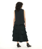 model in a black layered front sleeveless top with a cowl neck,  worn with a long tiered skirt in a matching fabric