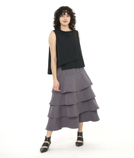 model in a black layered front sleeveless top with a cowl neck, worn with a long tiered skirt in a matching black fabric