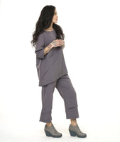 model in a slim grey pant with a matching pull over top. both pieces have asymmetrical seams along the body and legs.