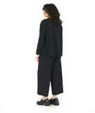 model in a black boxy pullover top with a v-neck and long sleeves, worn with a matching black wide leg pant. fabric has a pinched circle texture