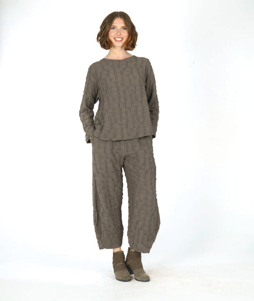 model in a boxy green pullover top with long sleeves and a matching wide leg pant with a tapered ankle. fabric has a pinched circle texture