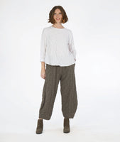 model in a boxy white pullover top with long sleeves and a matching green wide leg pant with a tapered ankle. fabric has a pinched circle texture