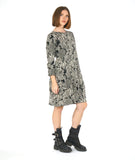 MODEL IN A BLACK AND WHITE LACE PRINT SHIFT DRESS WITH LONG SLEEVES AND A KNEE LENGTH HEM