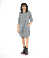 MODEL IN A BLACK AND WHITE ZIPPER PRINT SHIFT DRESS WITH LONG SLEEVES AND A KNEE LENGTH HEM