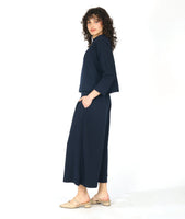 model in a black and blue zipper print paneled wide leg pant, worn with a matching pullover top with a dropped shoulder and a high neckline